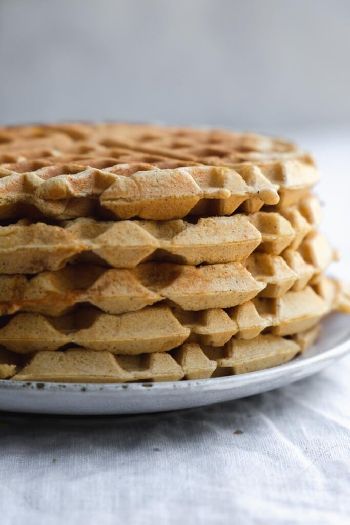 A super close up image of a stack of vegan pumpkin waffles to show the crispy geometric patterns on the side