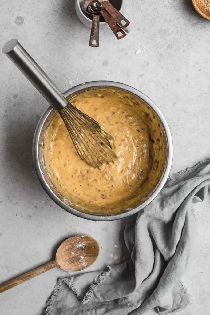 An overhead image of a mixing bowl with the sticky date cake batter inside before pouring in to the cake tin. The batter texture is loose but textured with dates. 