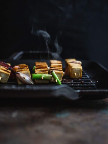 Tofu on skewers cooking on a hot grill
