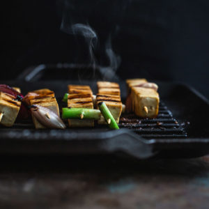 Tofu skewers cooking on a grill