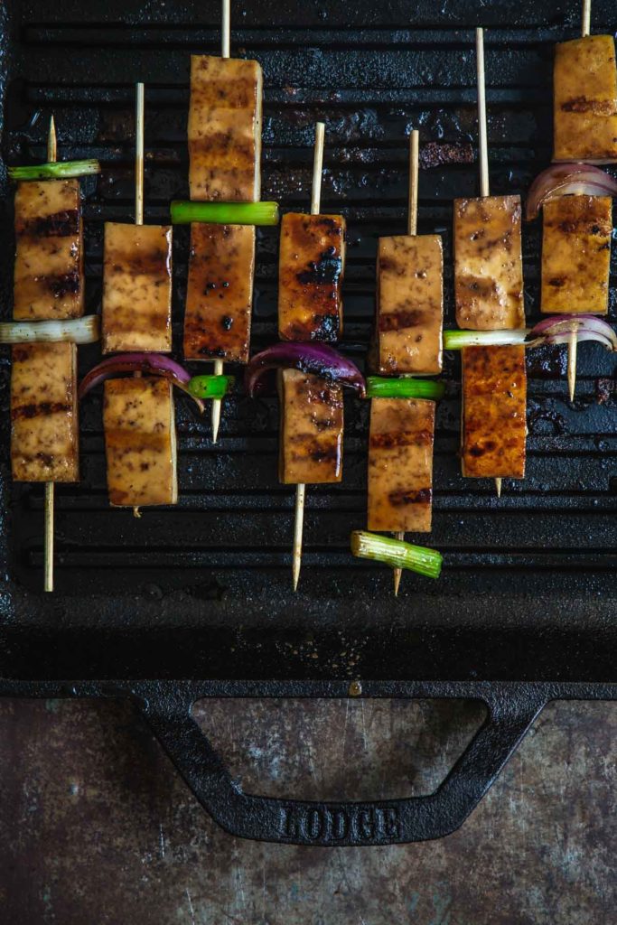 An overhead shot of the tofu yakitori skewers grilling on the Lodge Grill pan with deep grill marks on the tofu
