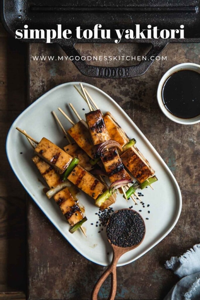 The finished grilled tofu yakitori skewers sit stacked on a rectangle white serving plate with a small bowl of dipping sauce nearby. Title text in white. 