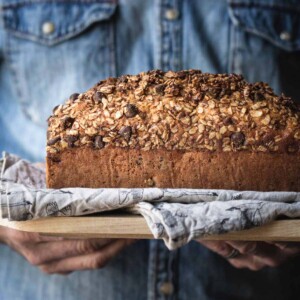 Close up image of hands holding banana bread on a board.