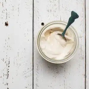 A birds-eye view of plant-based mayo in a jar on a table.