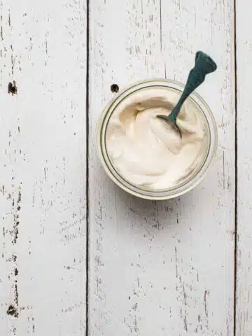 A glass jar full of vegan mayonnaise on a white table.