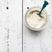 A glass jar full of vegan mayonnaise on a white table