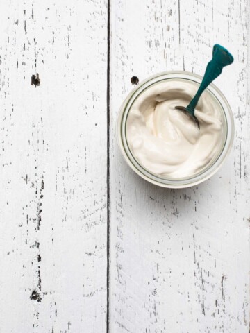 A glass jar full of vegan mayonnaise on a white table