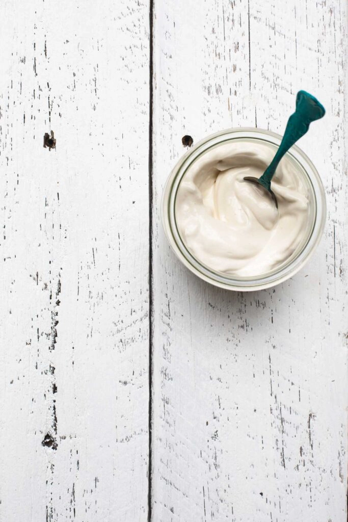 overhead image of a jar of vegan mayo on a white wooden background