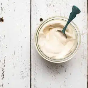 A birds-eye view of plant-based mayo in a jar on a table.