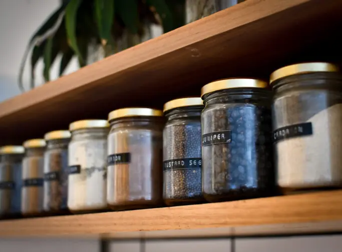 A shelf of labelled jars filled with different spices