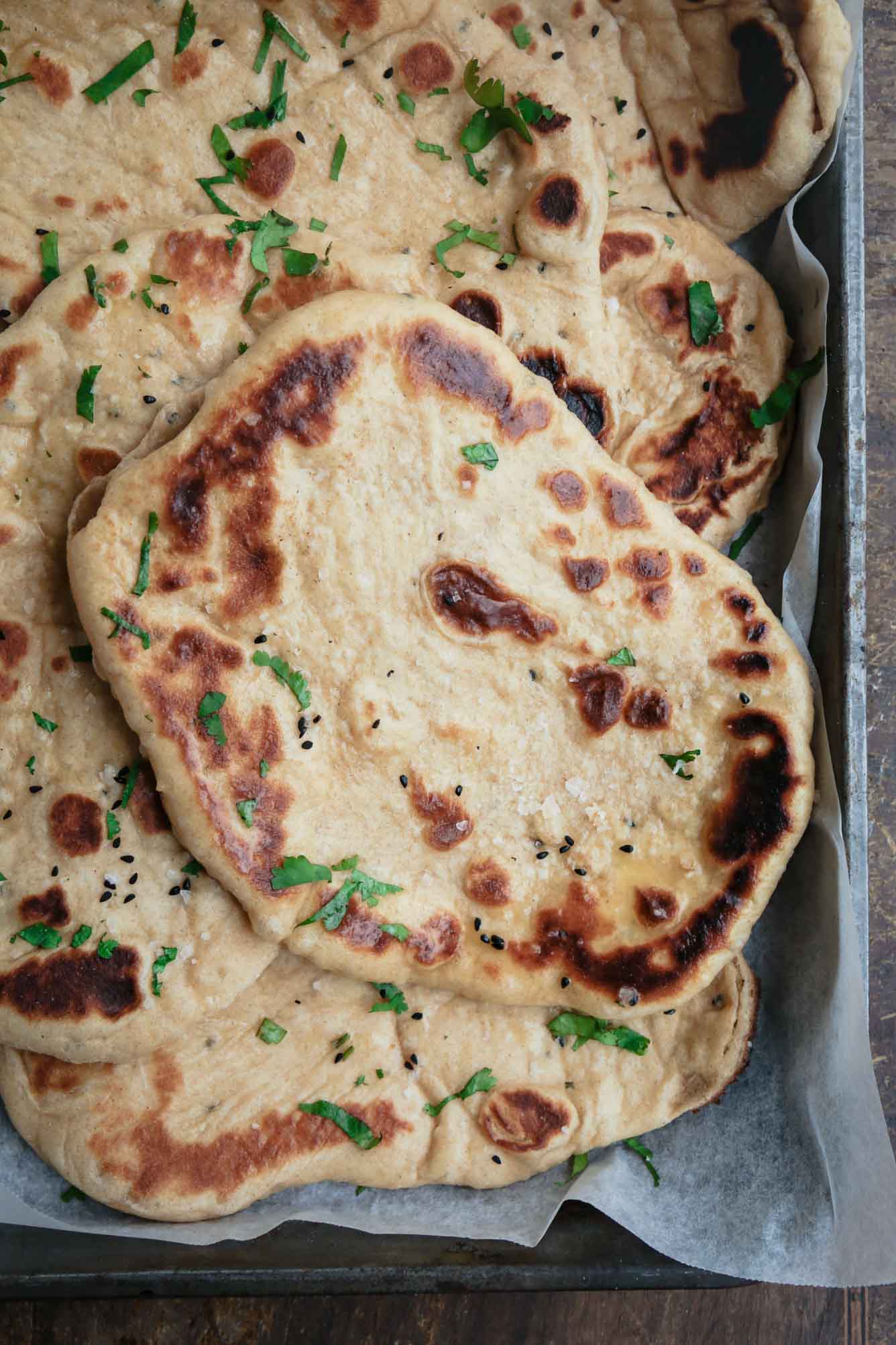 Overhead image of a freshly grilled pile of pillowy homemade vegan naan. 