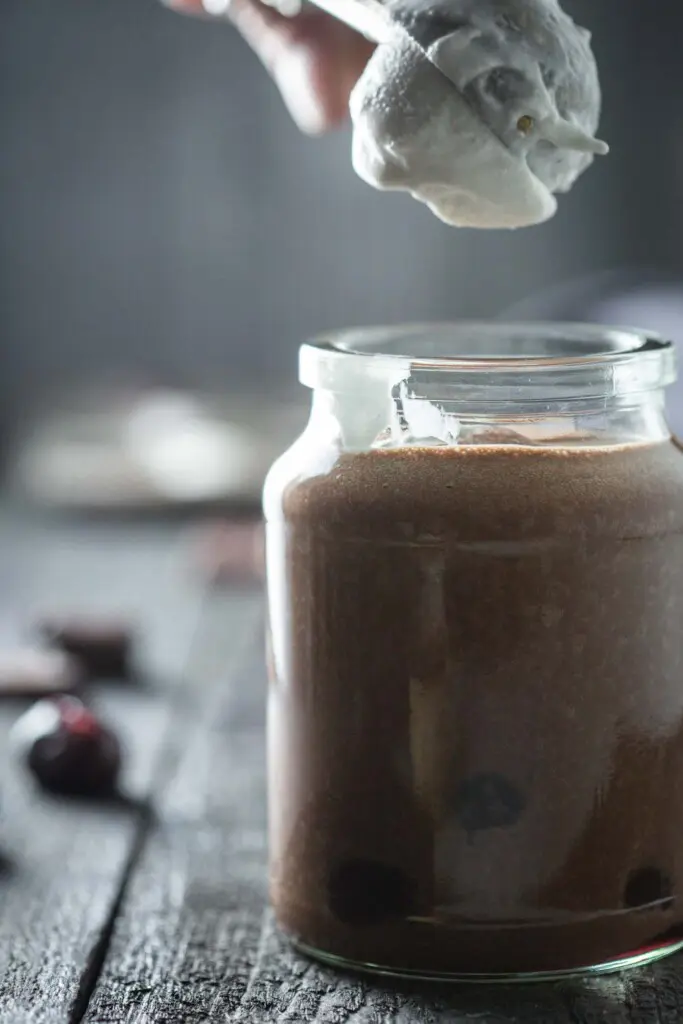 A scoop of ice-cream being added to a chocolate shake