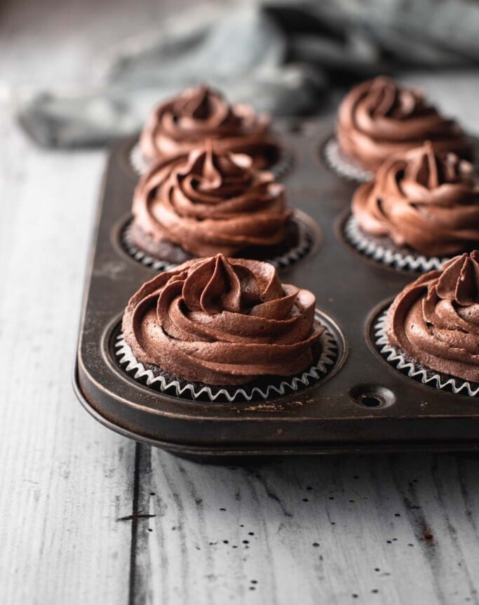 Front on image of a tray of cupcakes with chocolate buttercream swirls