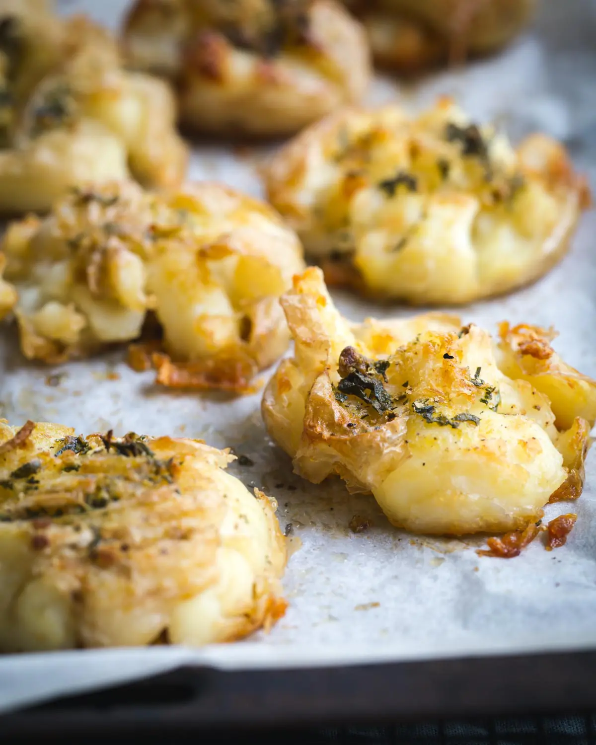 Crispy smashed potatoes with herbs on a roasting tray.