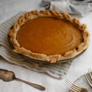 A set table with a pumpkin pie in the middle.