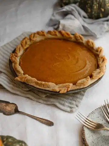 A set table with a pumpkin pie in the middle.