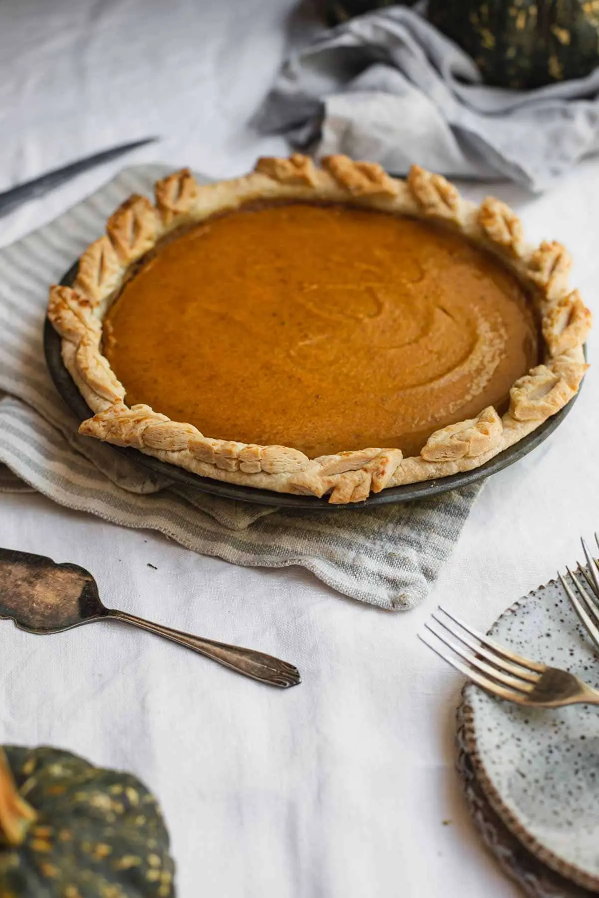 A set table with a pumpkin pie in the middle.