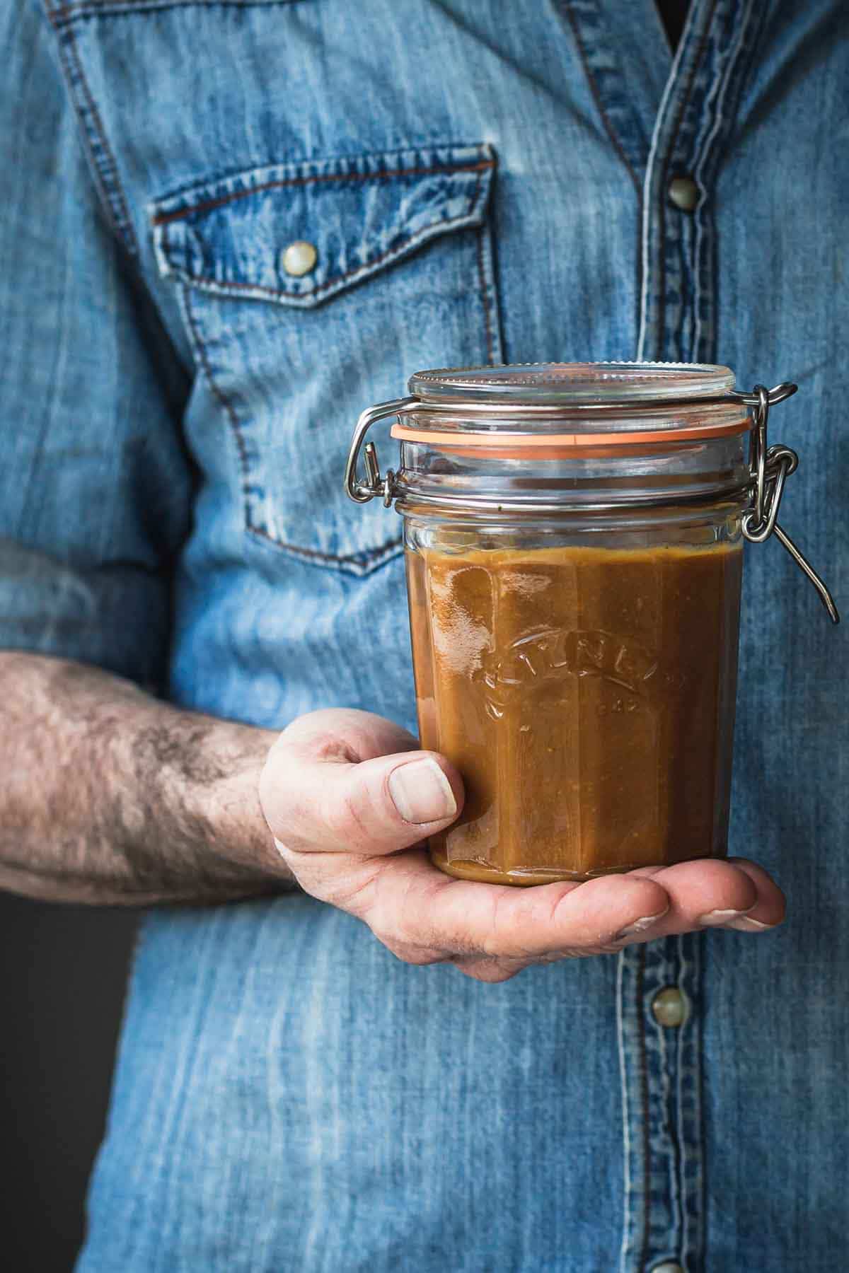 A man holding a jar of caramel.