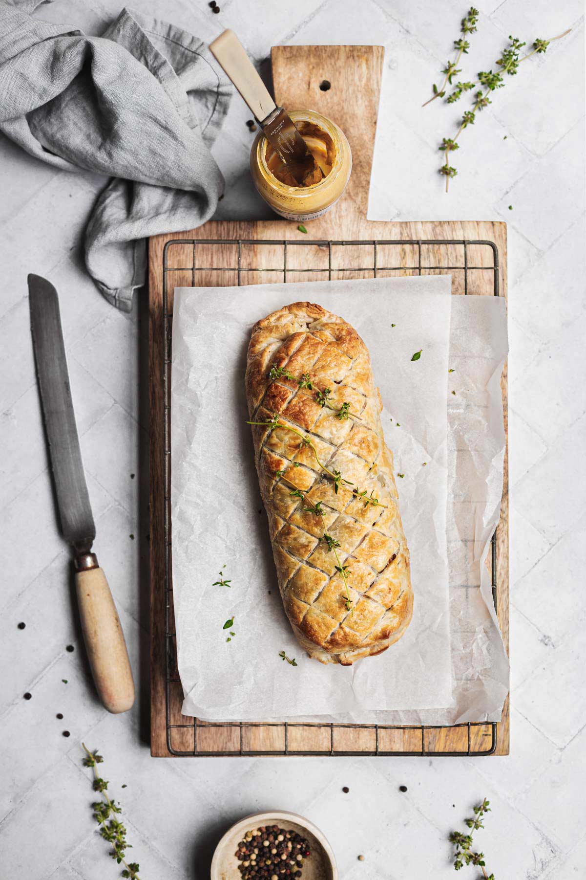 An uncut filled pastry roll on a cutting board on a table setting.