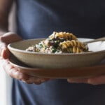 Man holding a bowl of mushroom pasta.