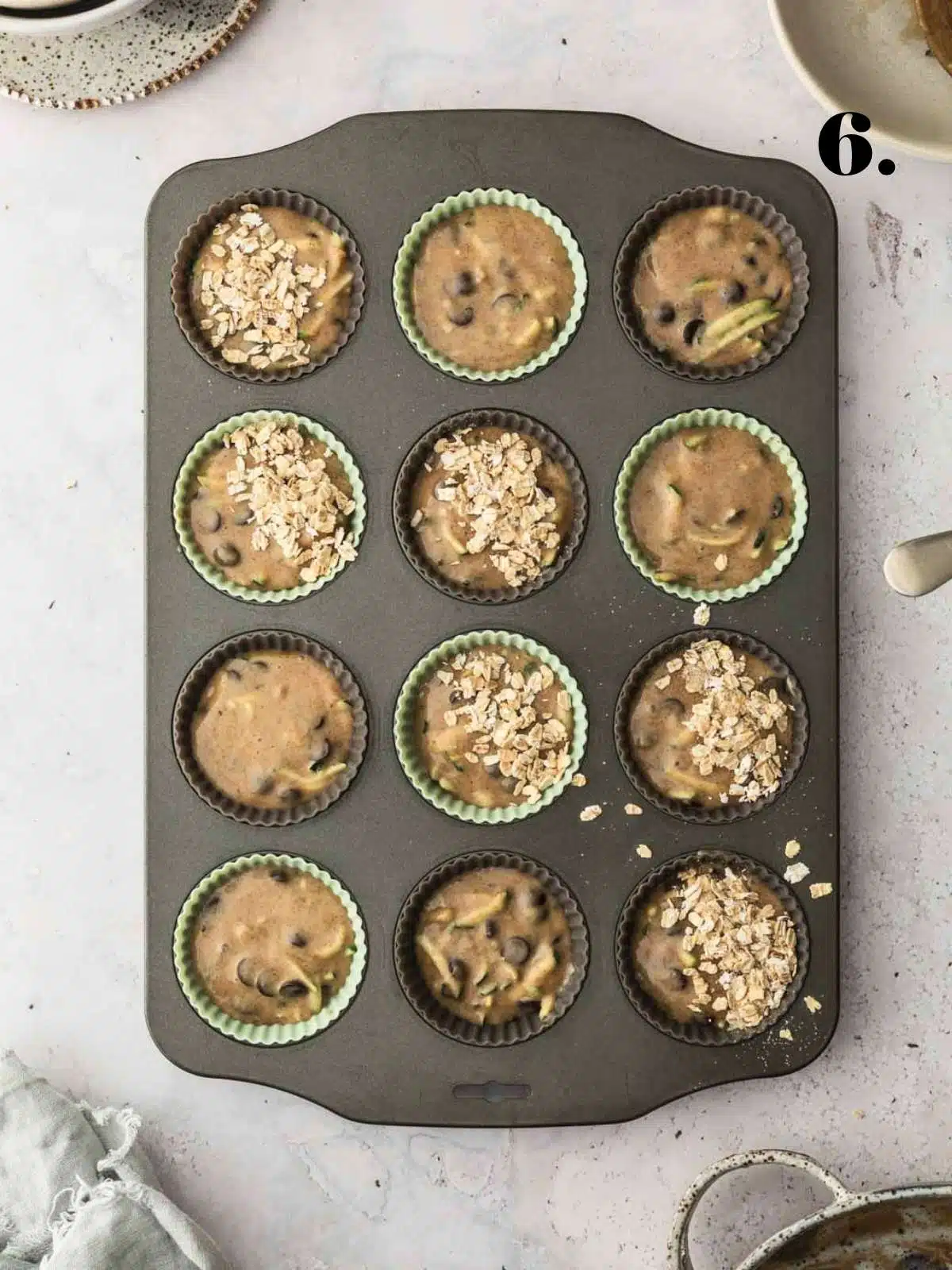 A muffin tray filled wit uncooked zucchini muffin batter before baking.