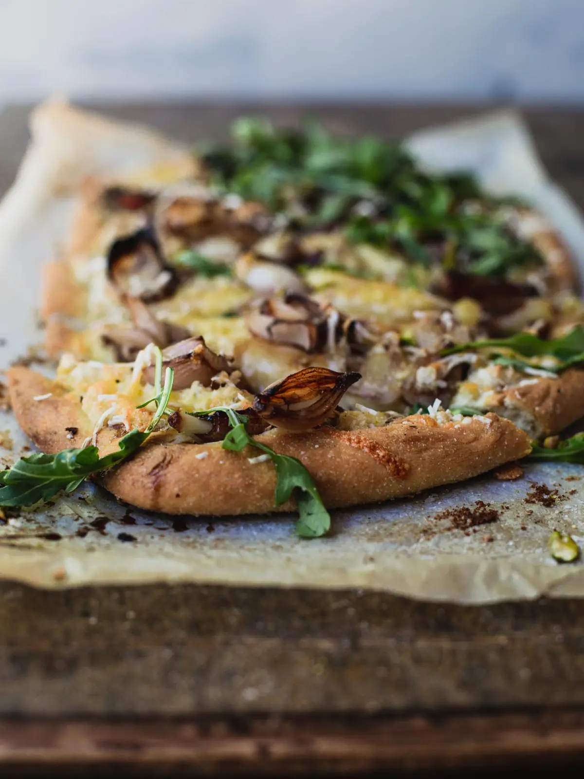 White pizza with green garnish on a wooden board.