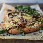 A white pizza with greens on a wooden board.