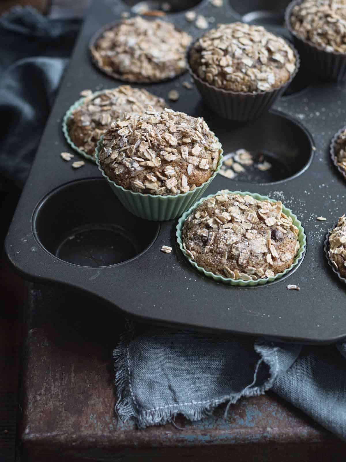 Zucchini Chocolate Chip Muffins with oat topping in a muffin tray.