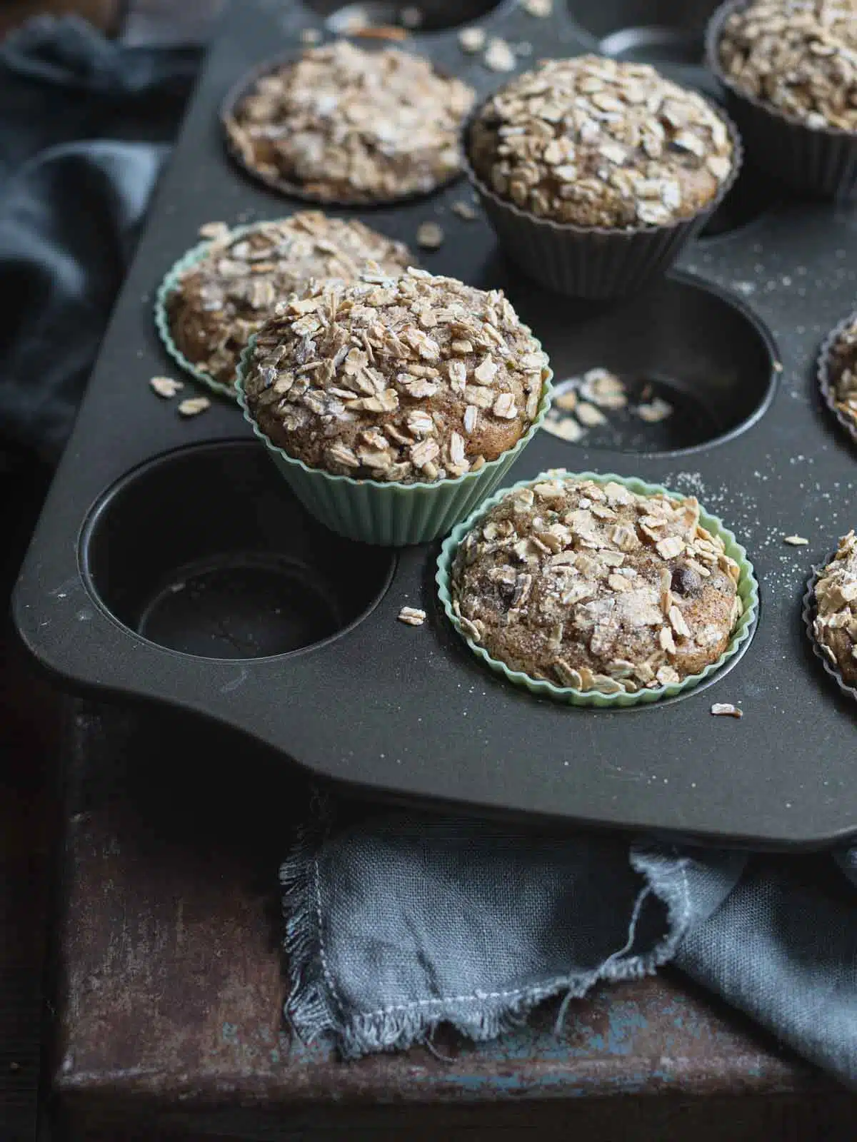 Zucchini Chocolate Chip Muffins with oat topping in a muffin tray.