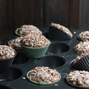 Freshly baked zucchini muffins with crunchy oat topping on a tray.