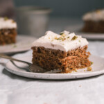 A slice of carrot cake with frosting on a plate.
