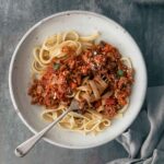A bowl of pasta with bolognese sauce.