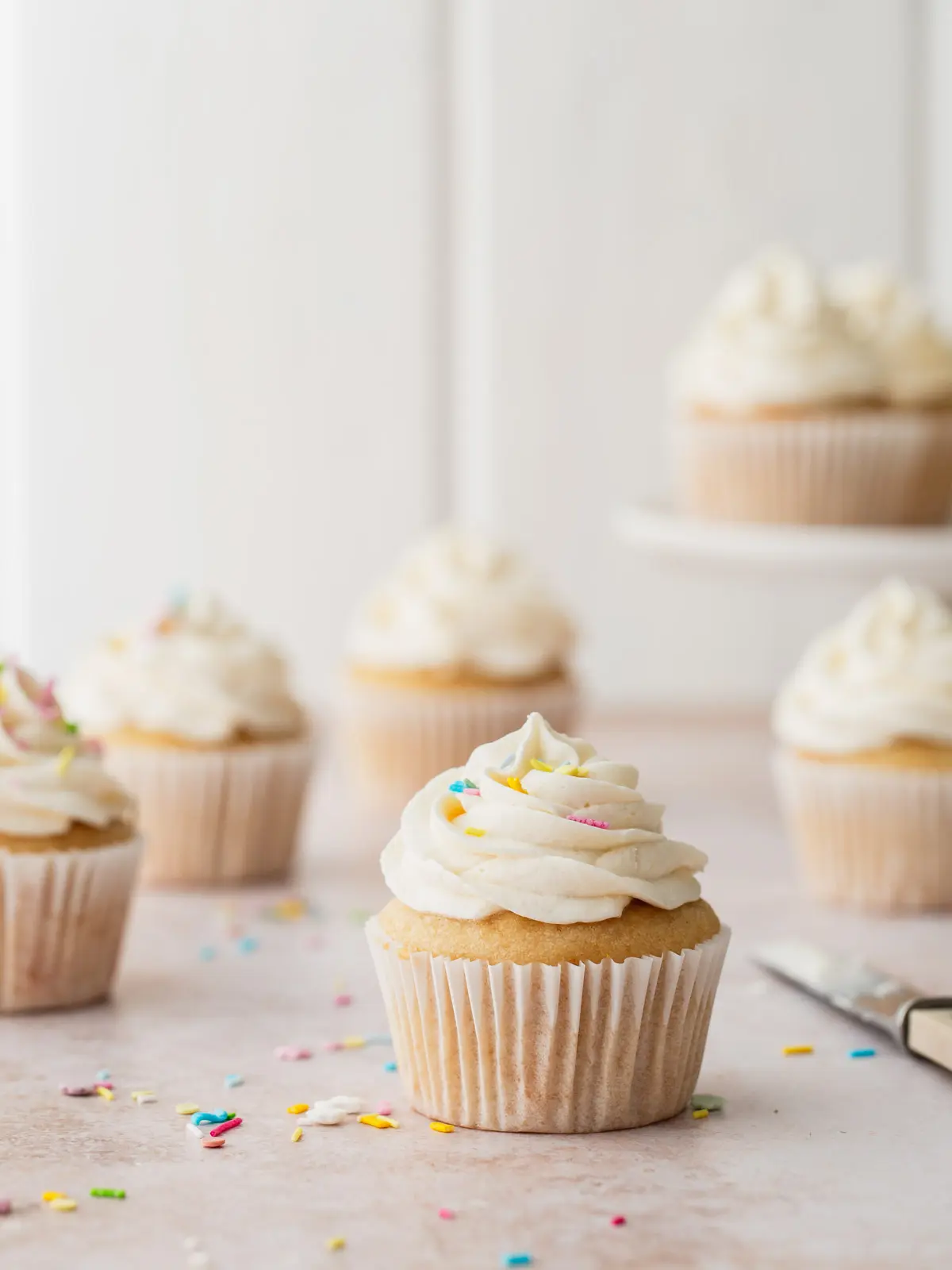 Frosted vanilla cupcakes with sprinkles.