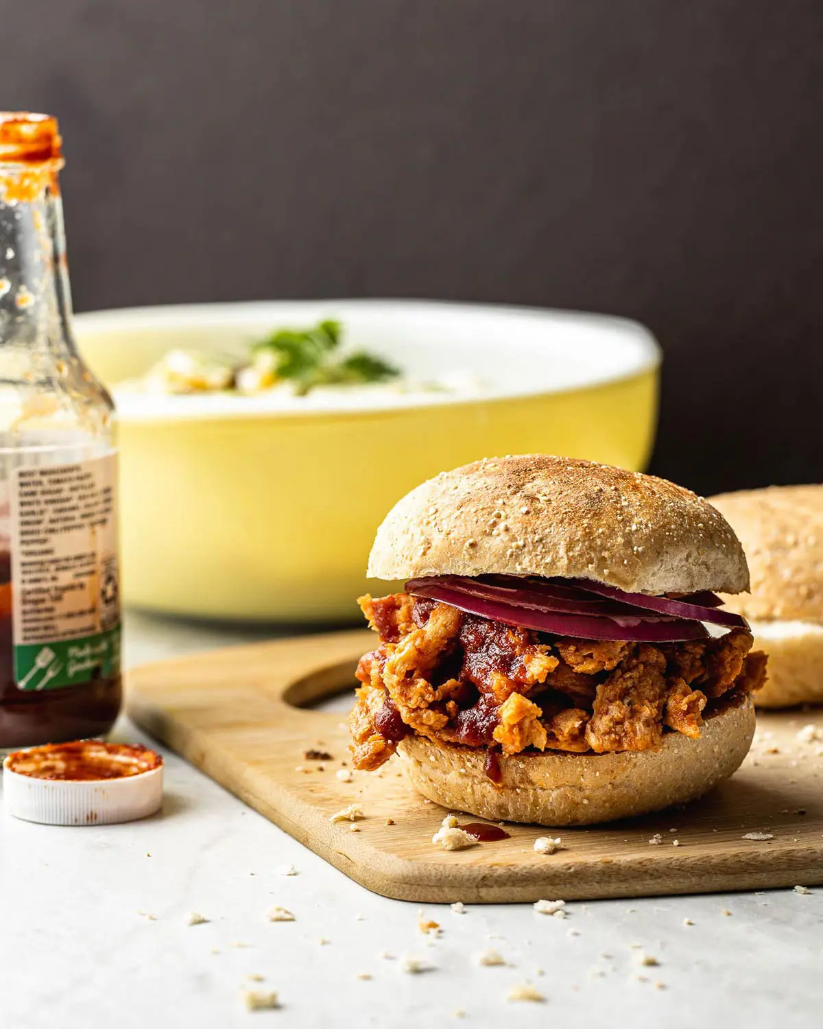 A veggie burger with sauce on a wooden board.