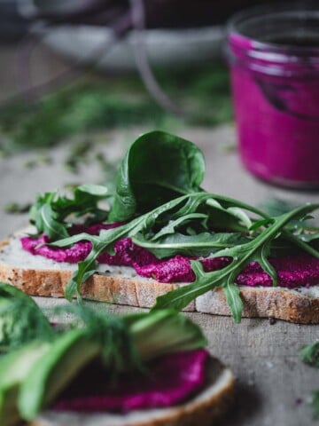 A slice of bread with beetroot hummus and greens.
