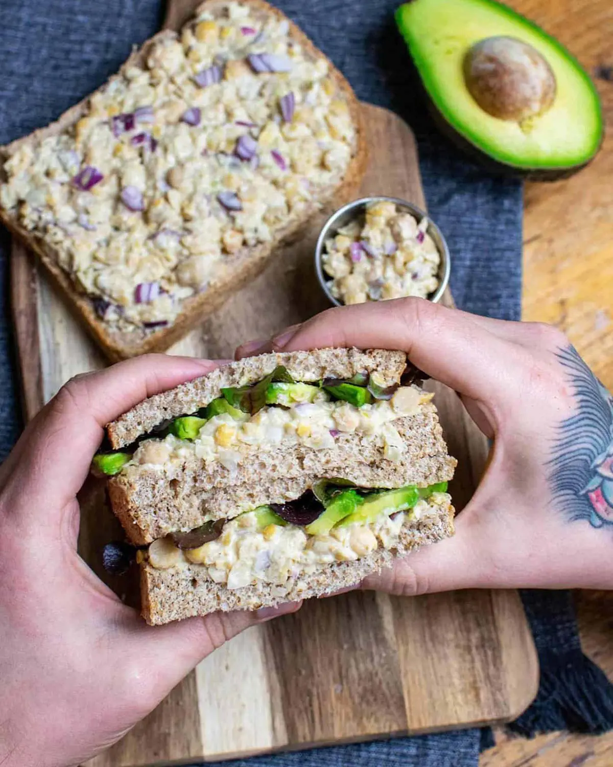 A man with tattoos holding a sandwich.