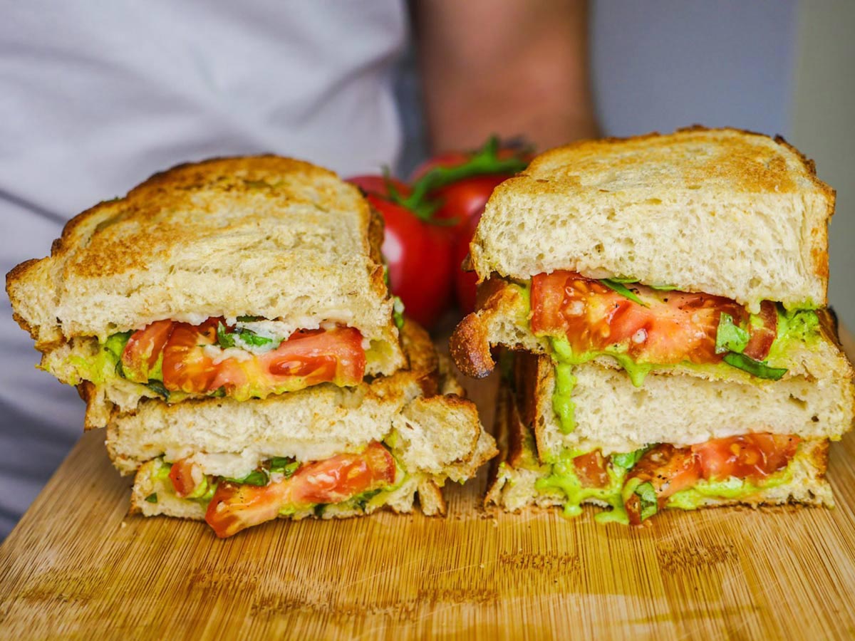 A stacked sandwich with tomatoes and avocado.