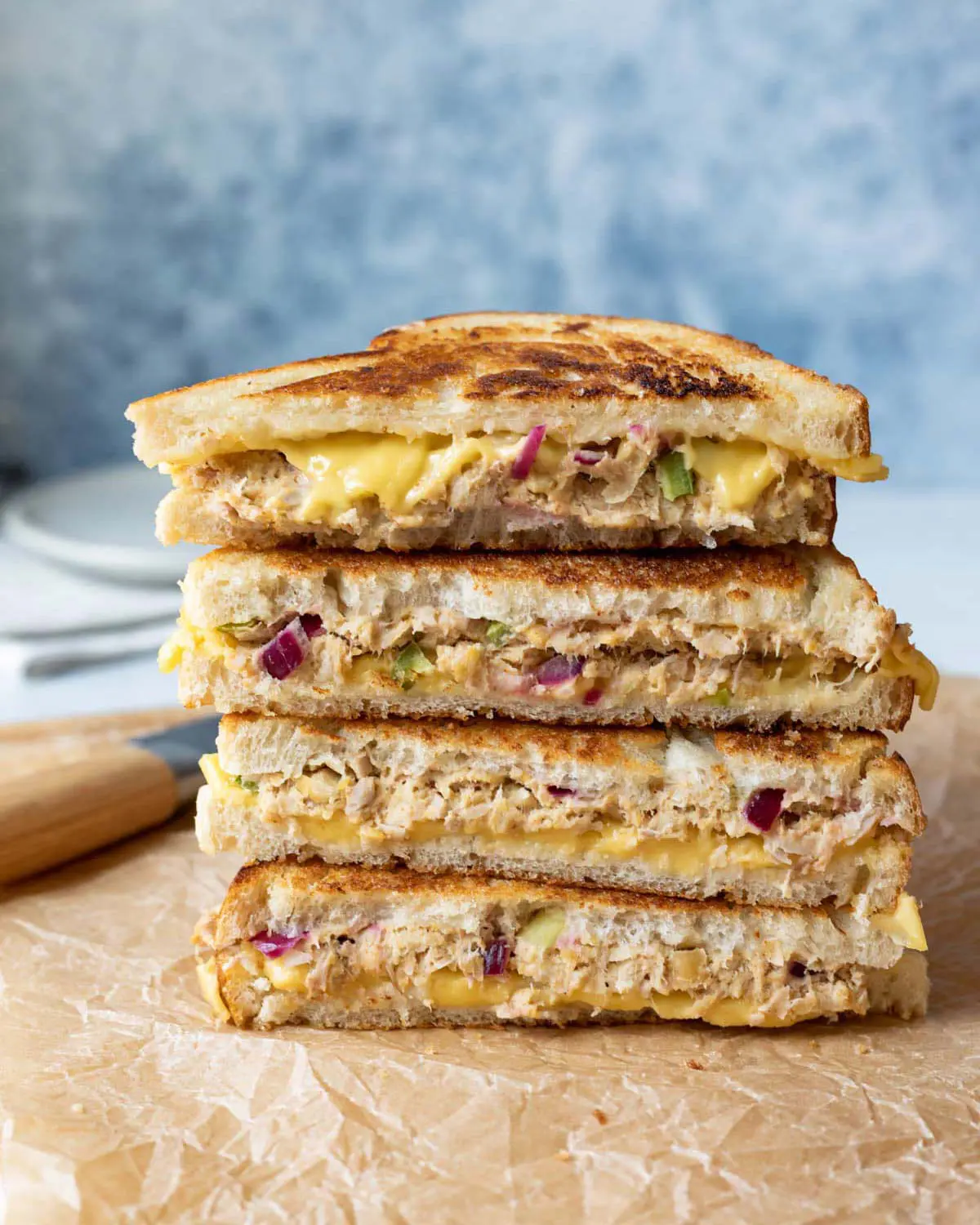 A stacked toasted sandwich on brown paper.