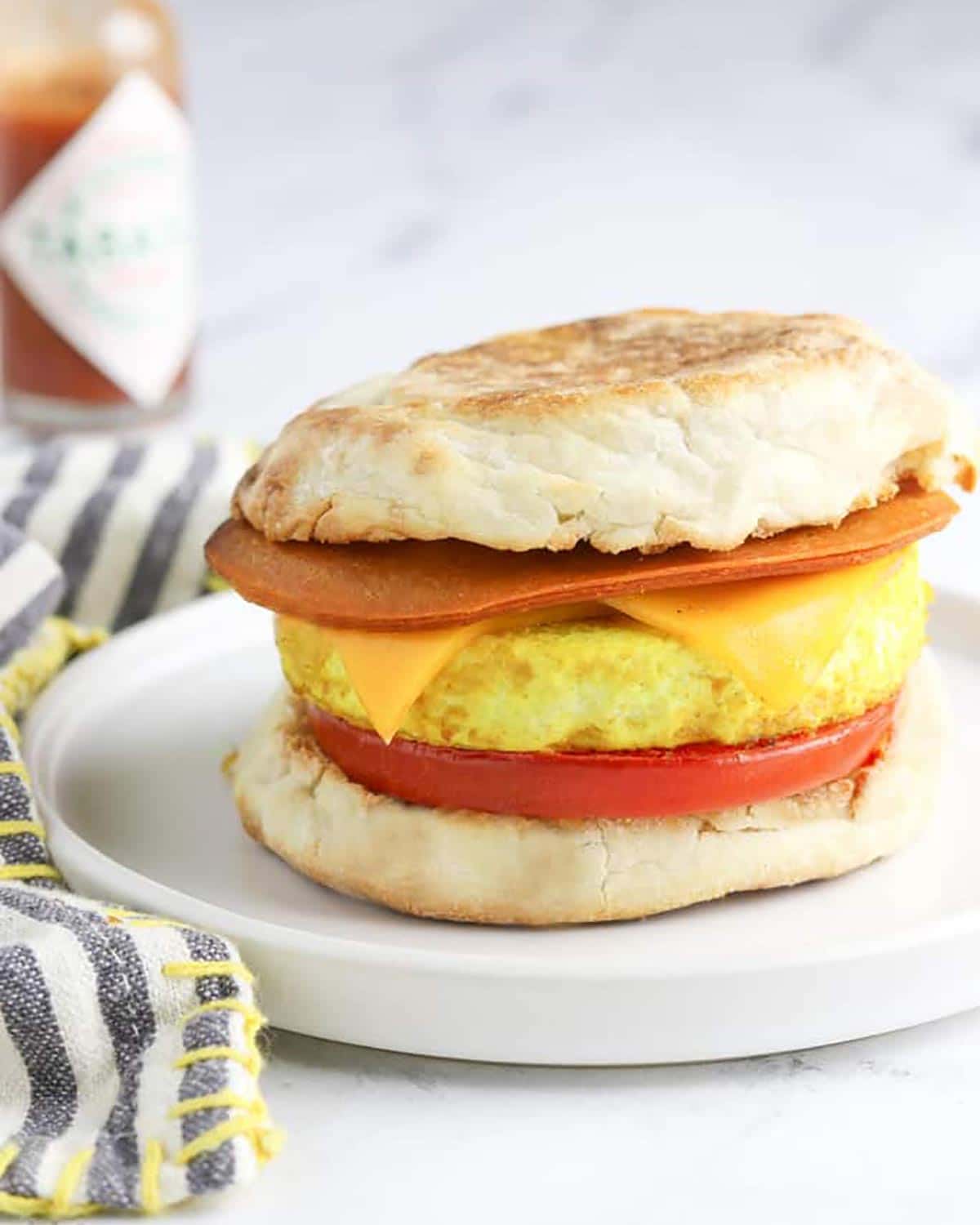 A English muffin with cheese, meat and egg.