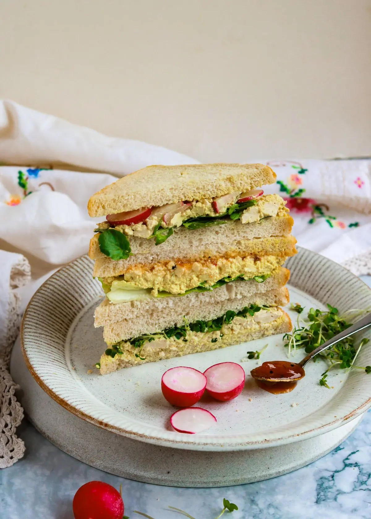 A plate of stacked egg and lettuce sandwiches. 