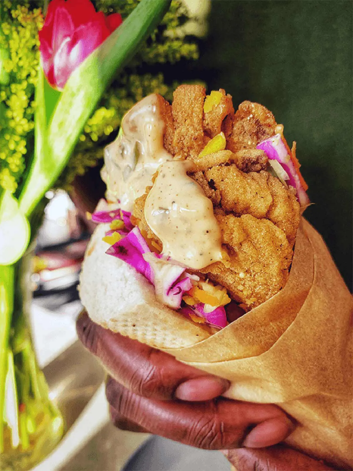 A hand holding a vegan o'boy sandiwich.
