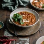 Bowls of lentil curry on a rustic wooden table.