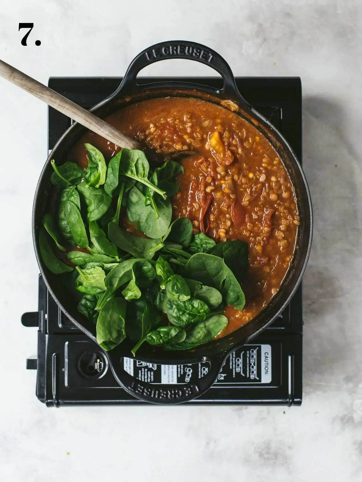 Fresh spinach added to a lentil curry in a pan.