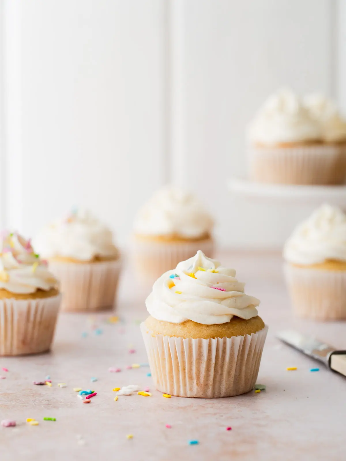 Vanilla cupcakes on a white wooden background. 