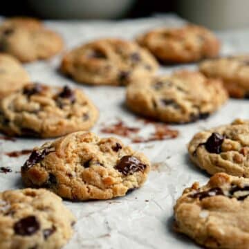 Freshly baked chocolate chip cookies on baking paper.