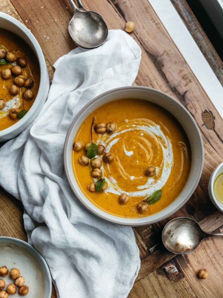 Two bowls of soup on a set table with napkins.