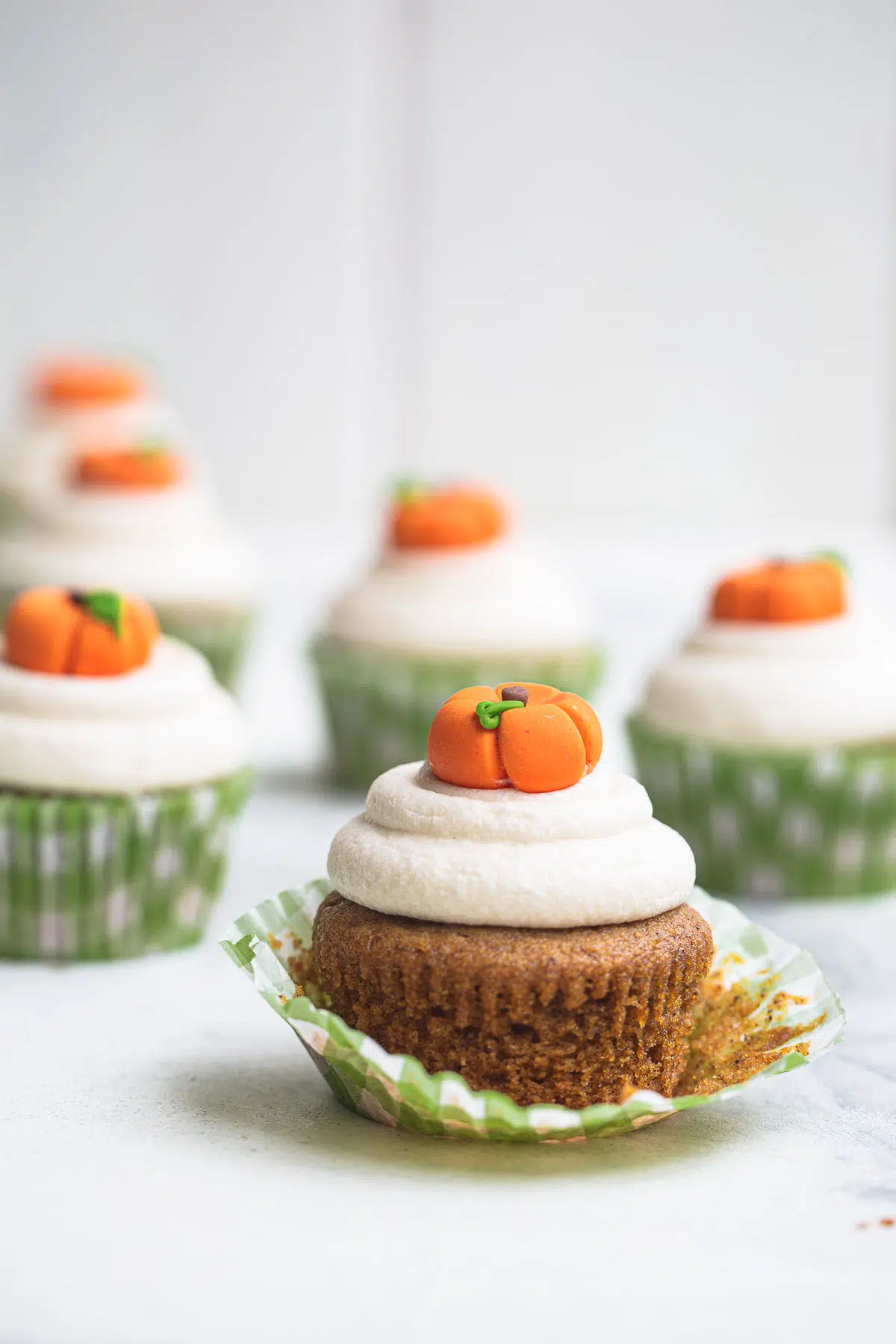 Pumpkin cupcakes with wrapper pulled down to show cake.