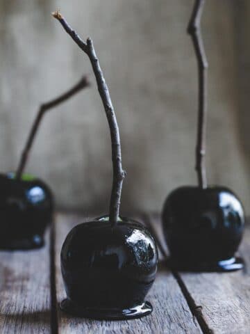 Black candy apples on a wooden table.