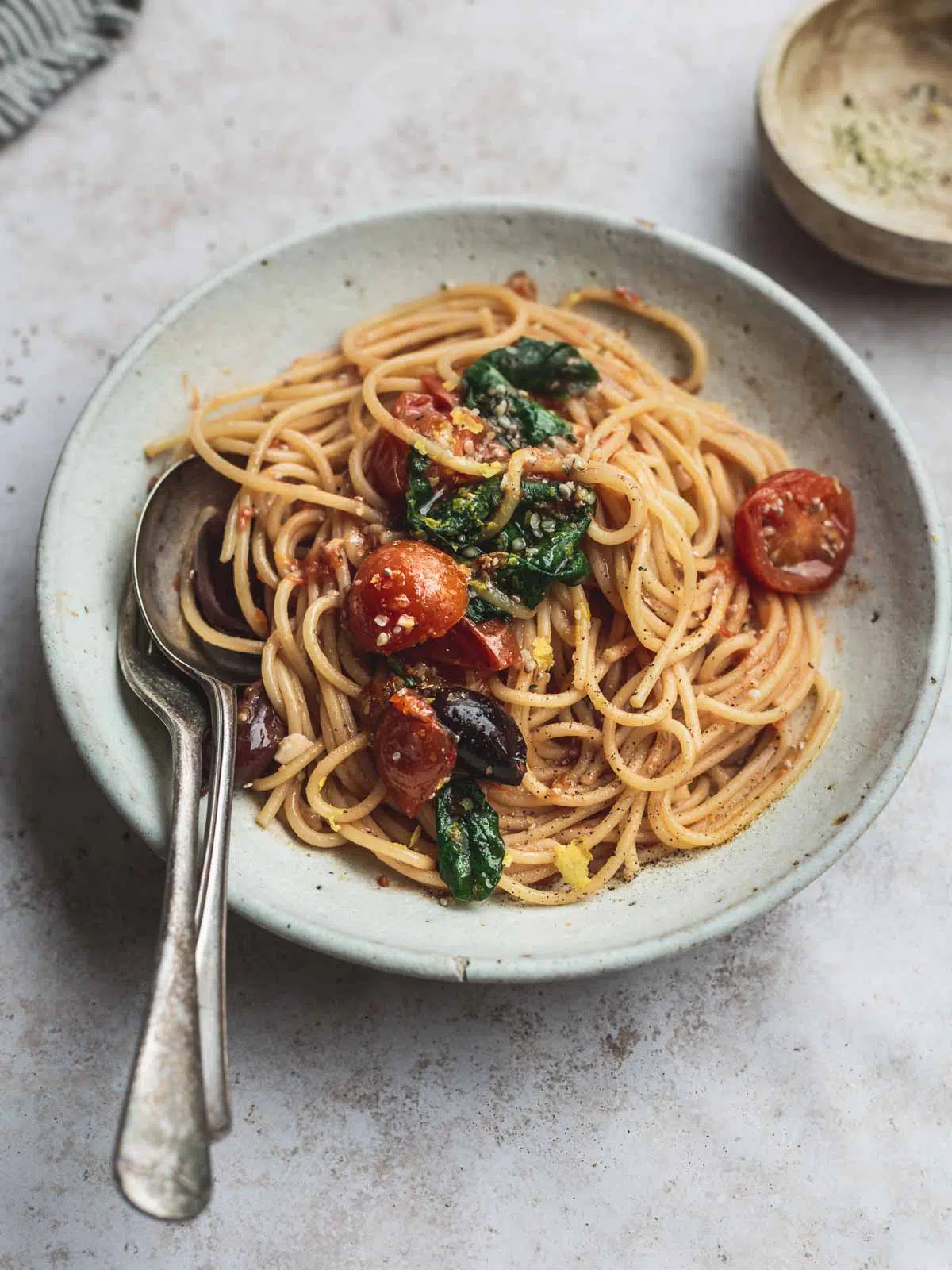 A bowl of tomato spaghetti with cutlery.