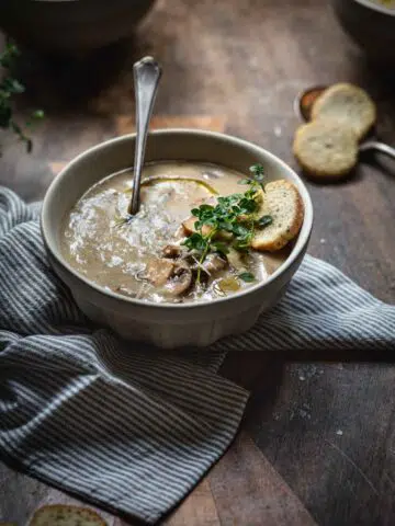 A bowl of mushroom soup on a wooden table.
